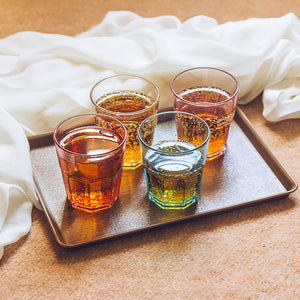 Four glasses of amber liquid on a appollo wooden tray 
