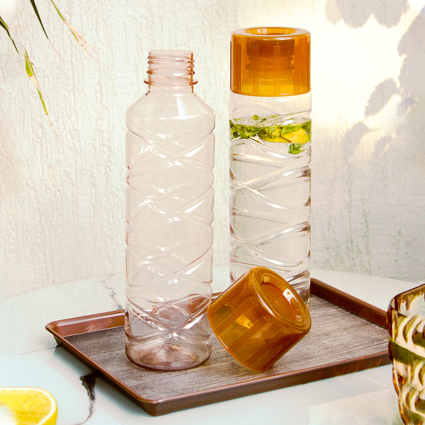 Two glass bottles with orange and clear designs on a wooden look brown tray.